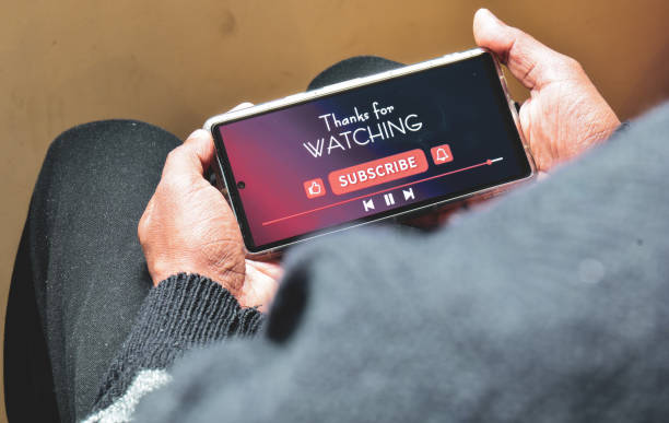 istock Man watching online streaming video footage on his smartphone. Channel subscriptions notification bell icon on Device screen. 1952247677