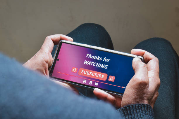 istock Man watching online streaming video footage on his smartphone. Channel subscriptions notification bell icon on Device screen. 1952248182