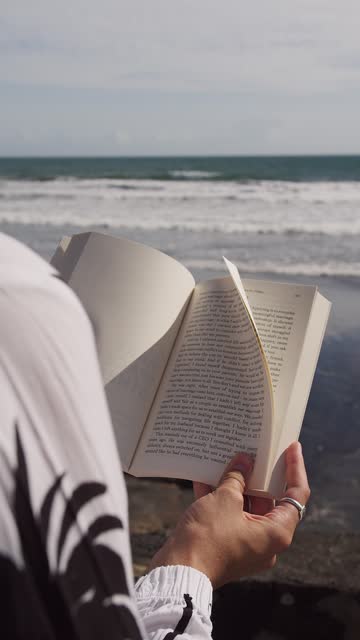 book in hands on the background of the ocean and waves. Vertical video