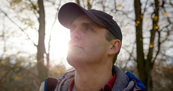 A portrait of a mid adult man enjoying a day out in nature at the weekend in a woodland area in Hexham, North East England. He is standing in nature and looking up at the view while the sun beats down on his face.

Videos available that are similar to this scenario.