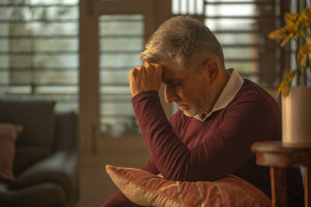 istock Worried old man touching head and sitting at home 1952269746