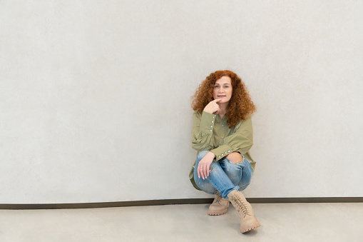 Redhead smiling woman in khaki shirt and jeans. High quality photo