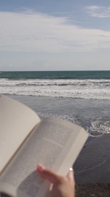 Book in the hands of a girl background of the ocean. Vertical video.