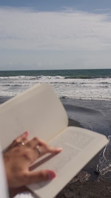 Book in the hands of a girl background of the ocean. Vertical video.