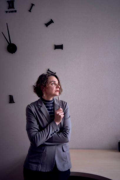 istock woman standing in office in front of clock 1952308882