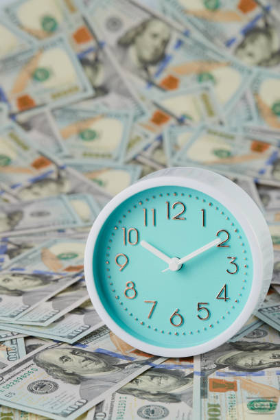 istock Round analog clocks are located on many hundred dollar bills. Vertical frame. 1952342327