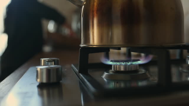 Kettle, gas burner and stove boiling in kitchen for hot coffee drink for morning breakfast, fire or stainless steel. Pot, tea appliance and apartment for warm beverage, matcha preparation or whistle