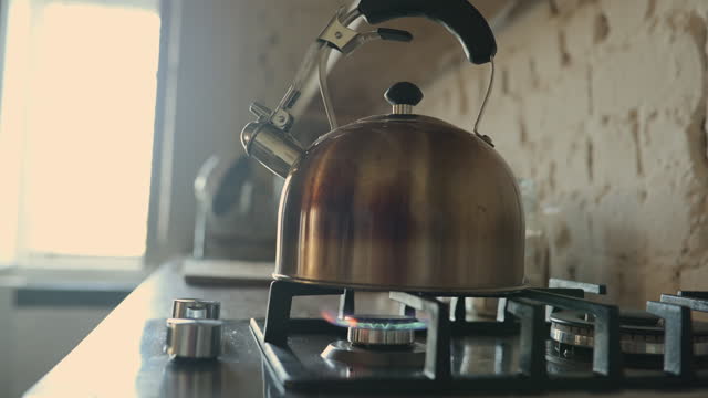Kitchen, morning and gas stove with kettle for coffee closeup in home for fresh drink, caffeine or warm beverage. Breakfast, counter and boiling water with metal appliance on fire in apartment