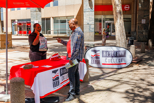 Sidewalk setup for college enrollment in Braamfontein, Johannesburg, with a student seen enquiring about courses available.