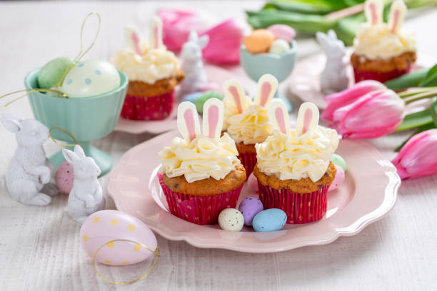 istock Carrot cake cupcakes for Easter. Carrot cupcakes with cream cheese frosting decorated with easter bunny ears on white wooden background. 1952350907