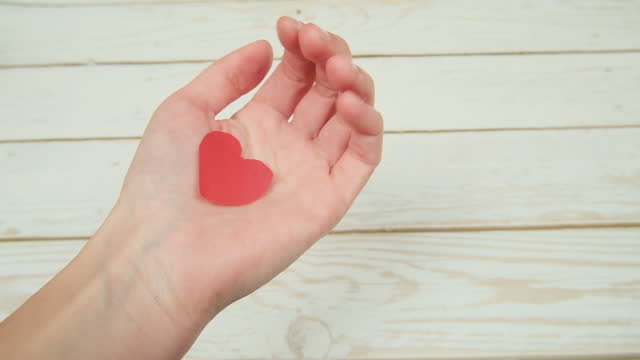 Woman hands holding red paper heart