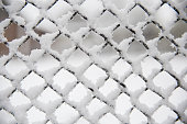 Snow lies on a metal fence.