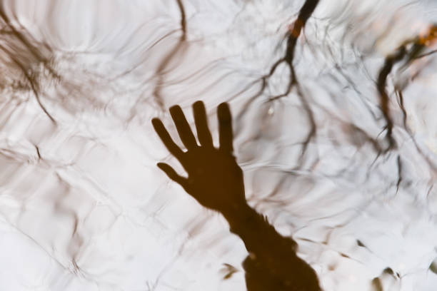 Blurred reflection of a human hand in the water. Abstract background image. The concept of reality testing when practicing lucid dreaming. Shamanism, lucid dreams, reality test.
