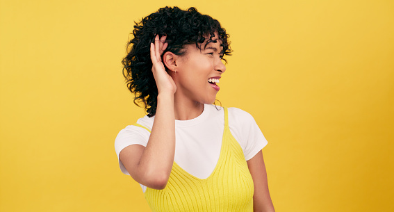 Hand, ear and woman in studio with deaf, gesture or speak up sign on yellow background space. Volume, secret and curious female model with palm emoji for listening to gossip, information or hearing