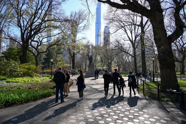New York City, New York, USA, April 10, 2023 - Tourists and locals stroll through Central Park, Christopher Columbus statue in the background, New York City.