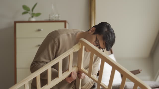 Asian man assembling  DIY Crib at nursery room