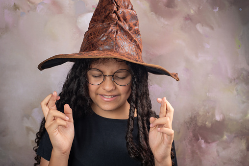 Teenage Brazilian woman with wizard hat and black shirt, abstract background, selective focus.