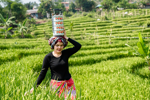 Smiling rural woman e carrying an iron gold pan in hand and a tiffin box (hampers) on her head to work Antique Tiffin Vintage Metal Food Carrier