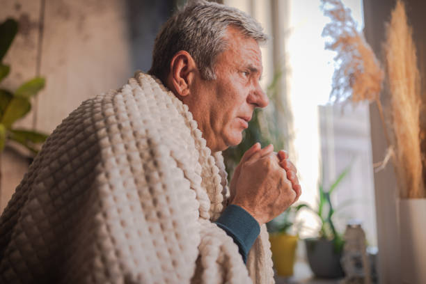 istock Energy crisis, a man sits next to a cold radiator with a blanket on his back 1952415101