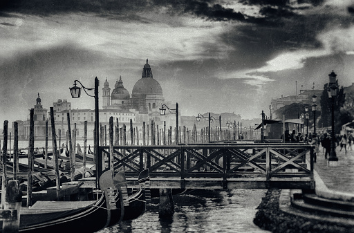 Looking out across a line of gondolas on the magnificent Grand Canal in Venice at sunset, with the majestically-domed Santa Maria della Salute Basilica in the background. Processed to resemble a vintage photograph.