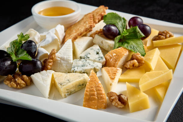 istock Cheese board with grapes and honey on a white plate against a black background 1952425511