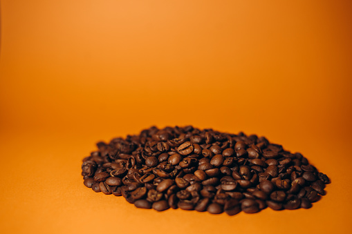 Roasted coffee beans on orange background