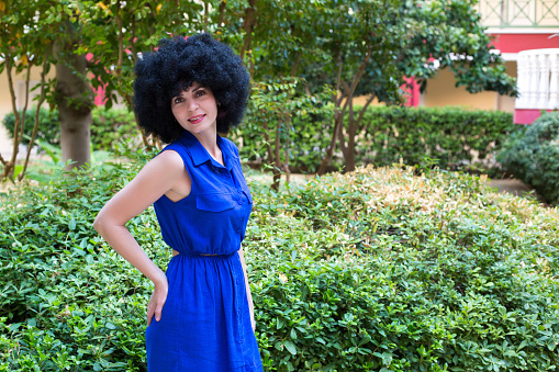 Portrait of a woman with black curly hair beautiful smile in a blue dress.
