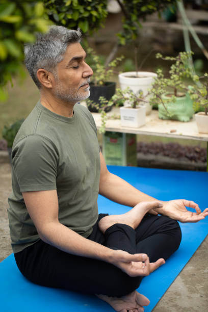 istock Old man meditating on yoga mat in yard 1952496442