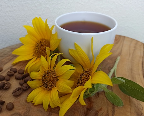 Hot coffee with coffee beans and sunflower flowers. Invigorating morning drink
