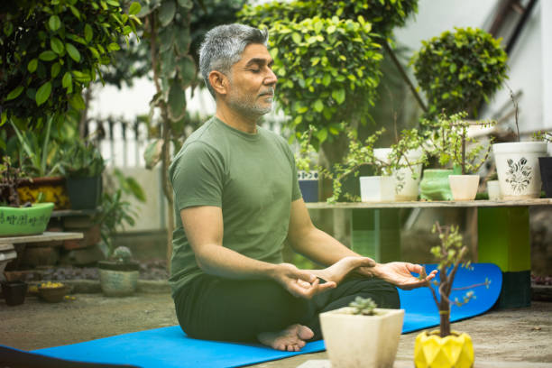 istock Old man meditating on yoga mat in yard 1952499613