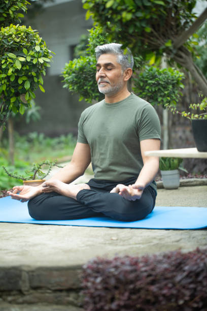 istock Old man meditating on yoga mat in yard 1952500646