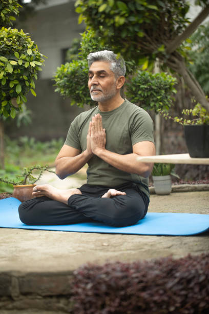 istock Old man meditating on yoga mat in yard 1952501169