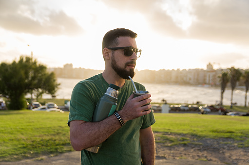 Man drinking chimarrão, mate (an infusion of yerba mate with hot water) at sunset in uruguay