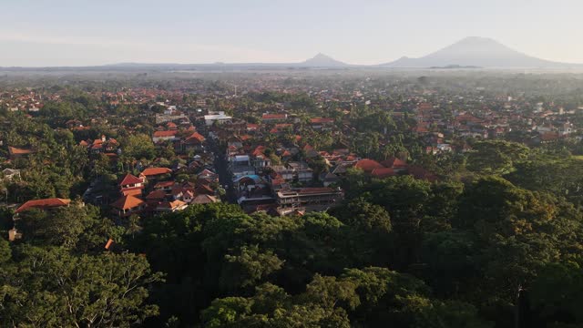 Cinematic sunrise view of Ubud town famous for traditional crafts with volcano Agung at the background and Monkey Forest at foreground