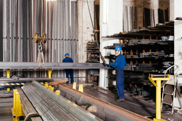 istock Male workers in metal workshop using crane to carry metal beams 1952519457