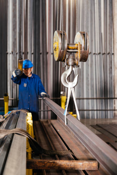 istock Male factory worker using crane to lift steel beam in workshop 1952520007