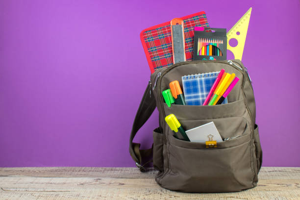 istock Backpack with different colorful stationery on table. Purple background. Back to school. 1952532265