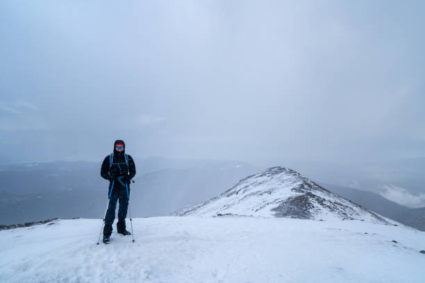 Alpinist climber is proud of himself and happy for being on the summit of a mountain