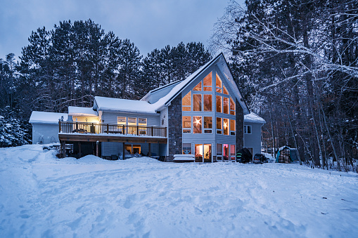 Lake House in winter time. Large home in wooded area on the water edge of the lake. Georgian Bay area of Ontario province, Canada.