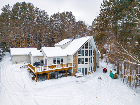 Lake House in winter time. Large home in wooded area on the water edge of the lake. Georgian Bay area of Ontario province, Canada. Drone point of view.