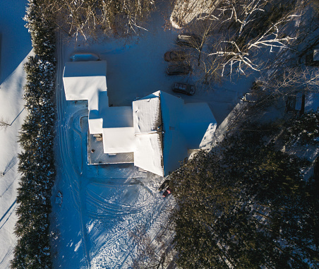 Sunrise view of Lake House in winter time. Large home in wooded area on the water edge of the lake. Georgian Bay area of Ontario province, Canada. Drone point of view.