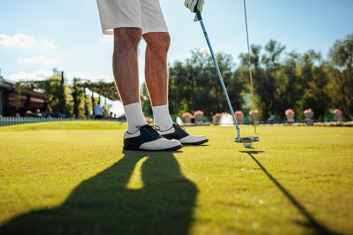 Shot of mans legs and grass while he is playing golf on the field and aiming to kick the ball