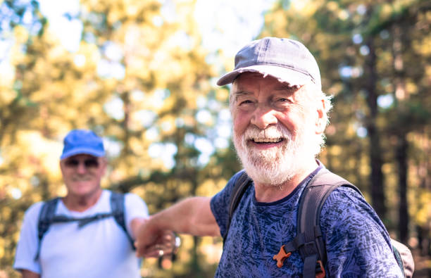 istock Happy smiling couple of elderly men with hat and backpack look in camera while enjoying mountain hike in the woods appreciating adventure and freedom, retired seniors and healthy lifestyle concept 1952602661