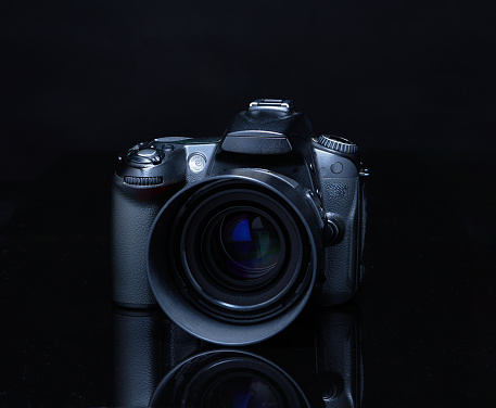 DSLR camera with lens attached, photographed with black on black background or low key photography