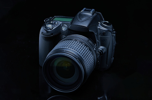 DSLR camera with lens attached, photographed with black on black background or low key photography