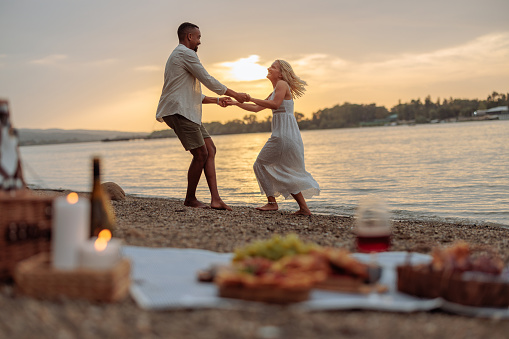 A multiethnic pair, an African-American man and a Caucasian albino woman, are dancing by the river at twilight, joyful and in love