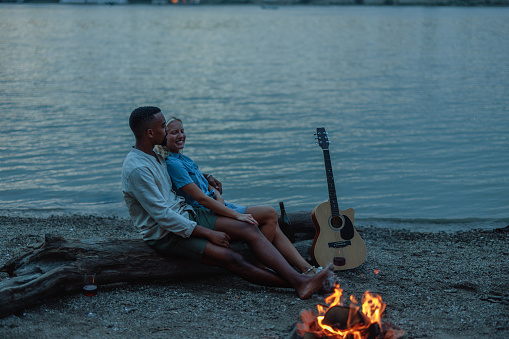 Lovely beautiful couple hugging and chilling with bonfire by the river side in the evening