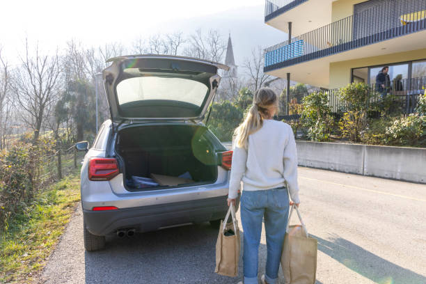 Diverse People Outside Their House With Their Cars\nTwo women outside their home with a car