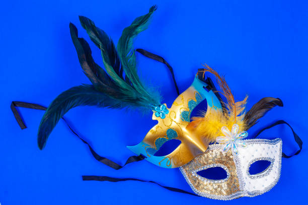 istock Two Venetian masks with feathers and glitter, isolated on a blue background 1952632363