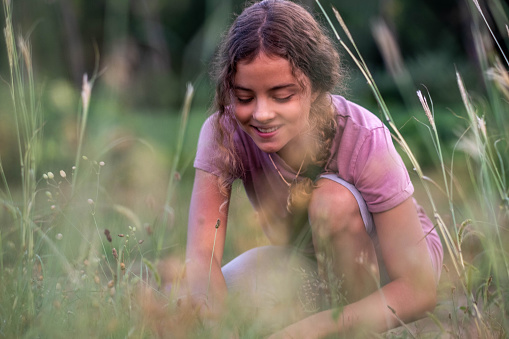 teenage girl picking flowers in nature, smiling